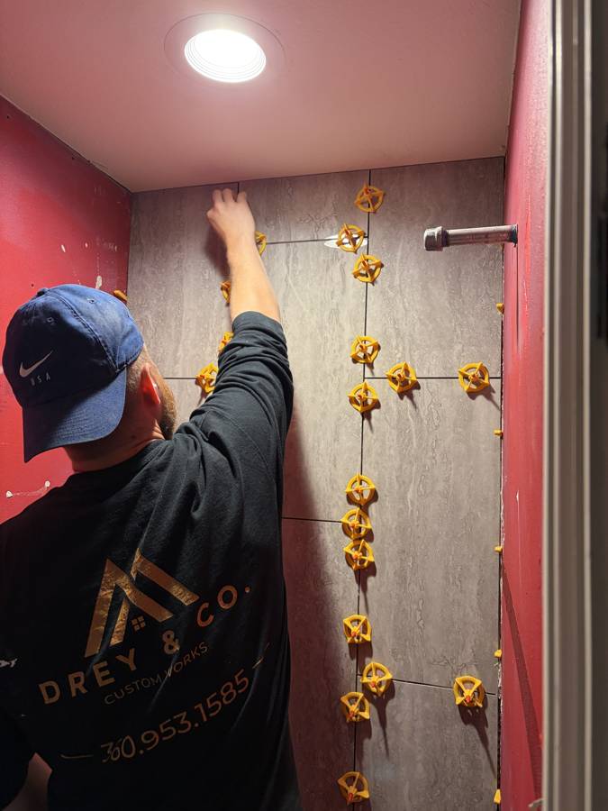 Setting large-format shower tile with a leveling system