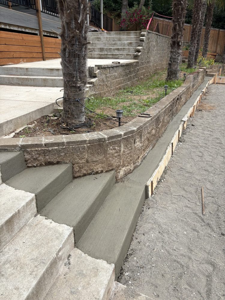 New concrete steps and walkway poured along a retaining wall
