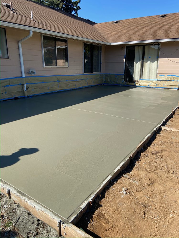 Large new patio slab poured along the back of a house