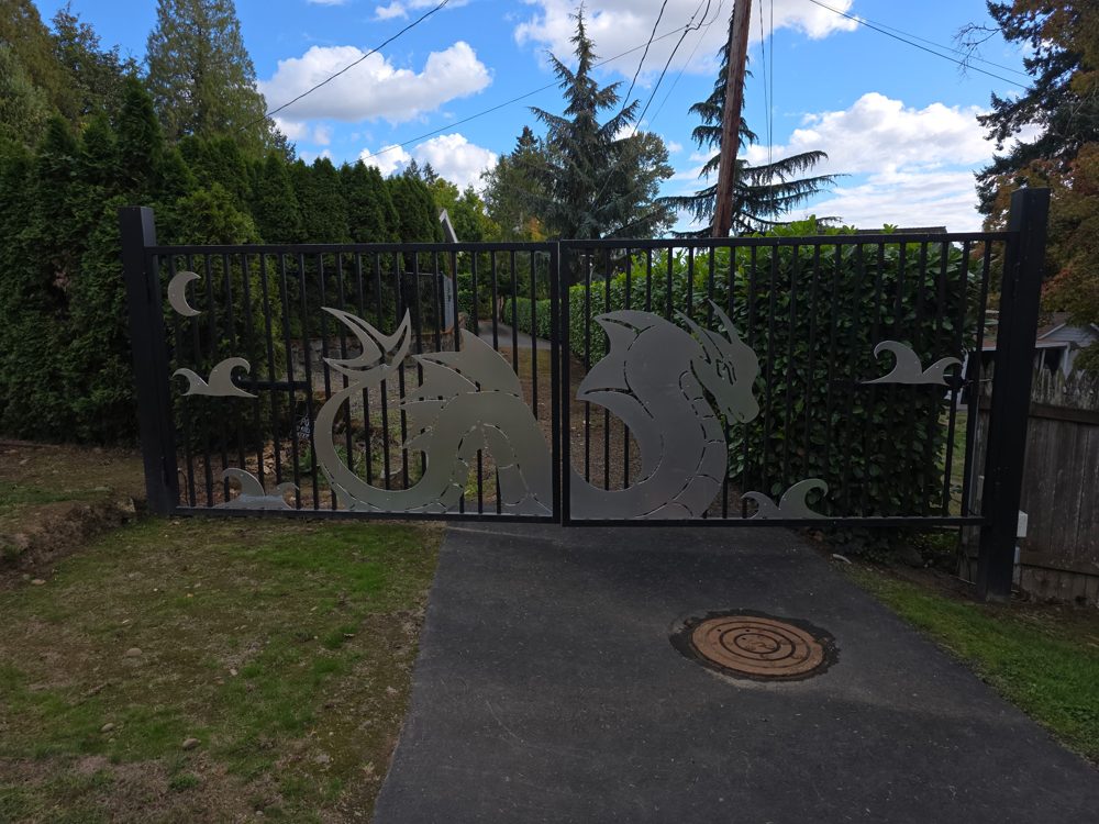 Custom iron driveway gate with a stainless steel sea dragon, waves and moon