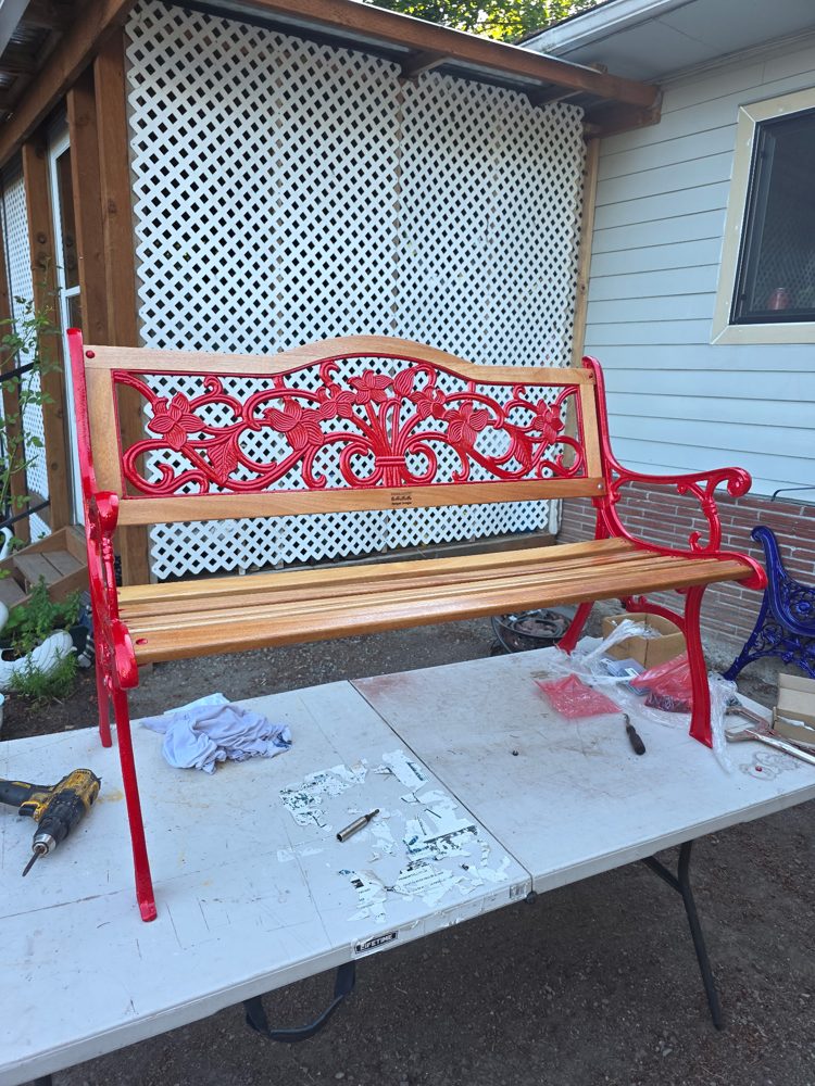 Restored cast iron bench in bright red with a floral back panel and new wood slats