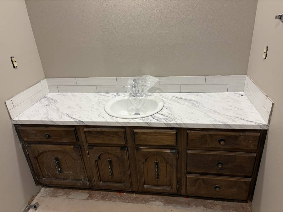 Long bathroom vanity with new countertop and tile backsplash