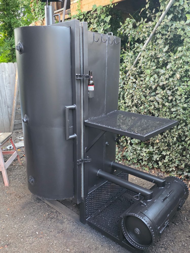 Custom-built vertical steel smoker with offset firebox, side shelf, hooks and bottle holder