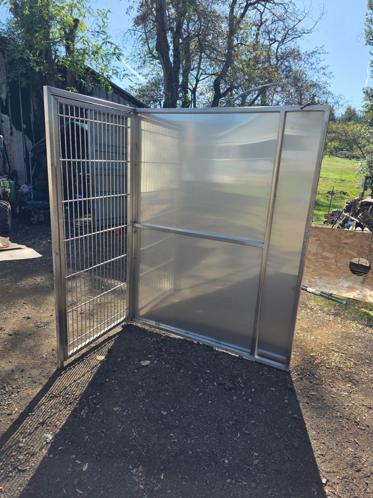 Custom stainless steel dog kennel with a welded wire gate and solid divider panels