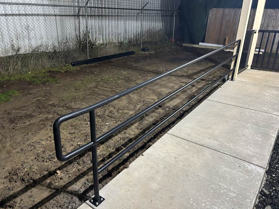 Three-rail steel guardrail along a new sidewalk
