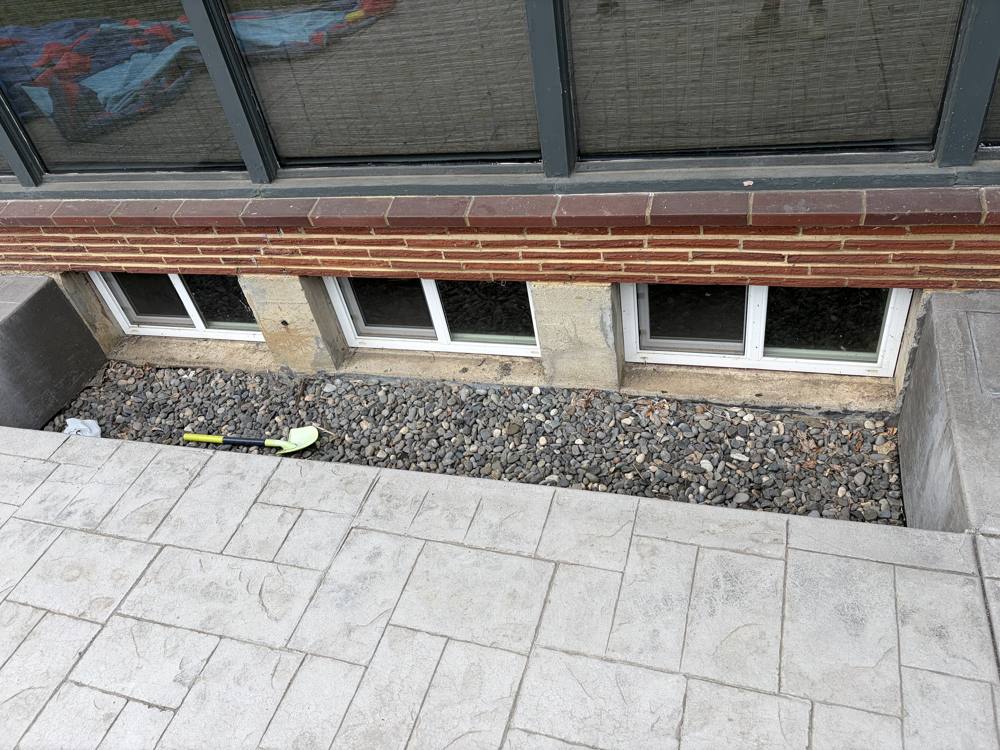 Basement window wells with new white windows and clean gravel
