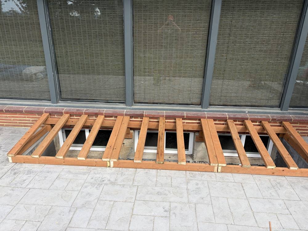 Long lumber frame over a row of window wells
