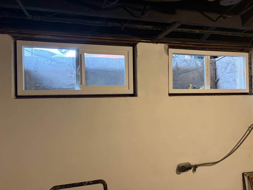 Two new basement windows installed in a masonry wall