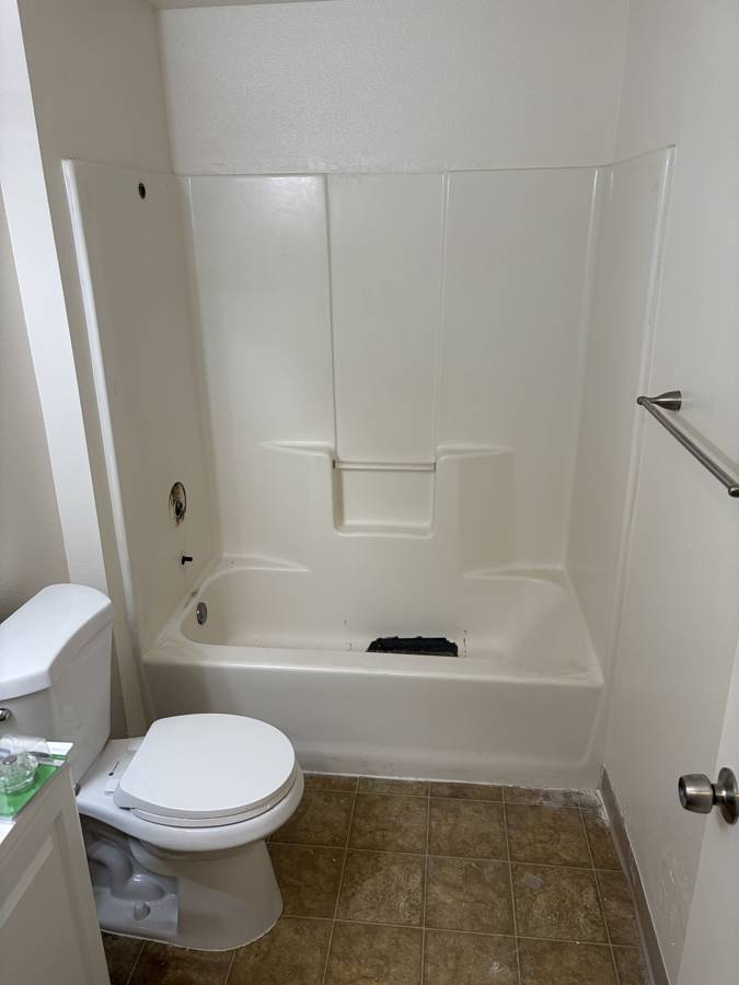 Before: old tub with a damaged, patched floor