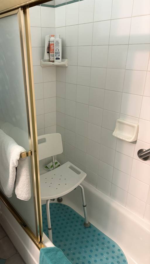 Before: tub with a shower chair and sliding glass doors