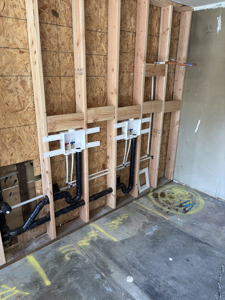 Washer boxes, drains and supply lines roughed in between new studs