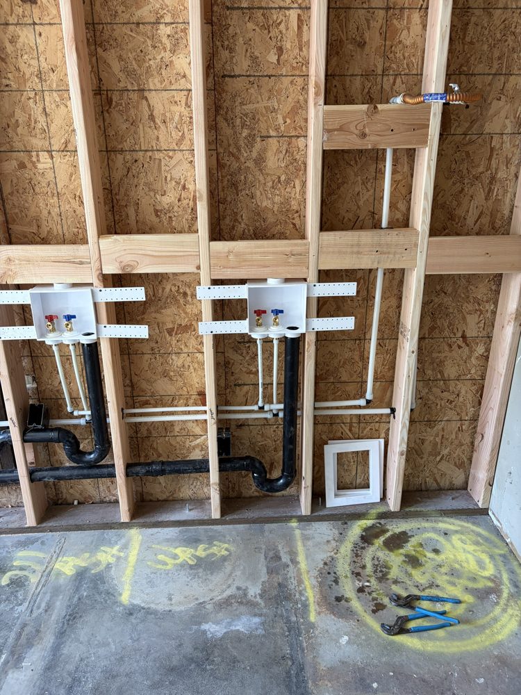 Close-up of two washer outlet boxes with new supply lines and drain traps