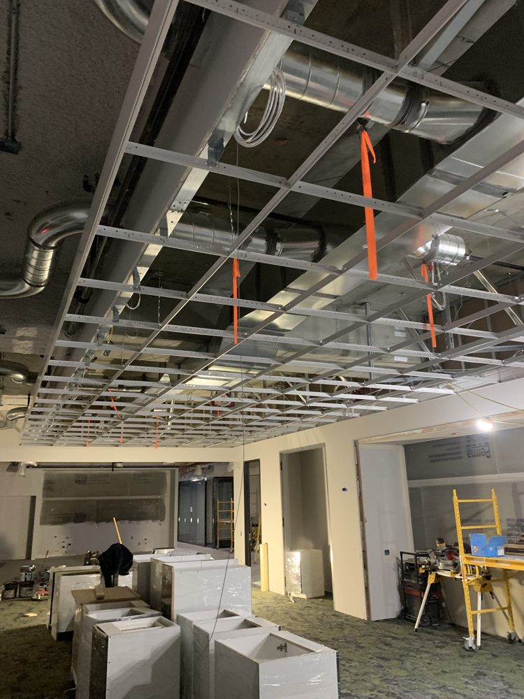 New ceiling grid installed below ducts in an office build-out