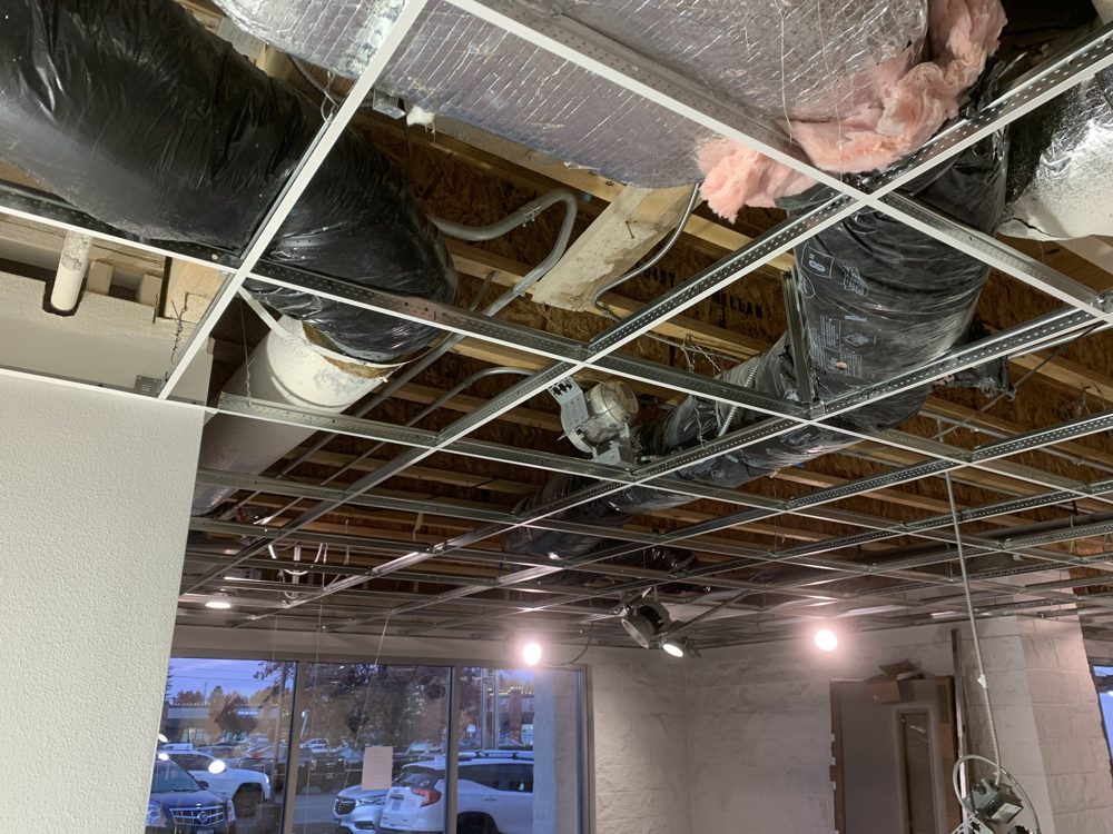 Ceiling grid with new can lights being installed in a retail space