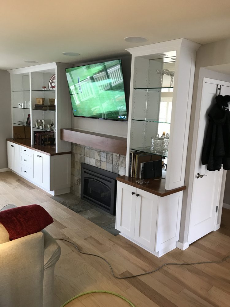 Custom built-in cabinets and glass shelves around a fireplace